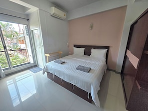 Habitación de hotel con cama, ventana y equipo de aire acondicionado.
