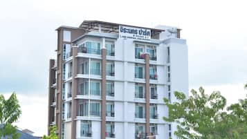A multi-story residential building with balconies, a satellite dish, and a sign with contact information.
