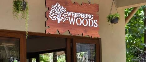 Puinen kyltti, jossa lukee ”Whispering Woods”, on ripustettu puisen parvekerakenteen yläpuolelle.