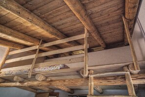 Techo de madera con vigas a la vista y una escalera.