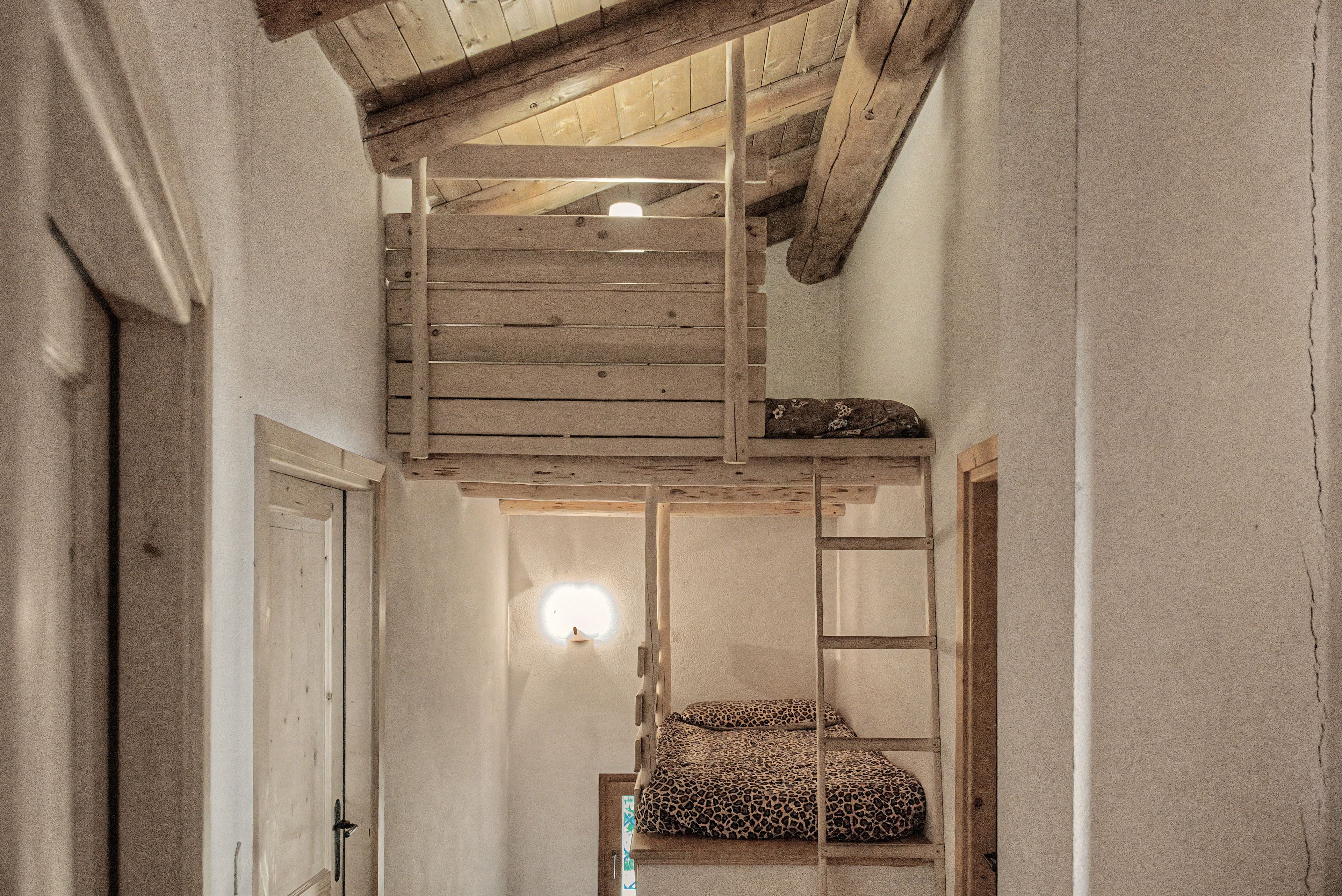 Un corridoio stretto con un letto a soppalco in legno e una scala per accedervi.