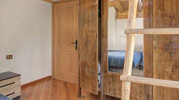 Ein Zimmer mit Holztür, einem Bett mit blauer Matratze und einem kleinen Holzschrank.