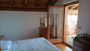 Ein Schlafzimmer mit einem Bett, einem Holzkapmierer, einem Spiegel und einer Glastür zum Außenbereich.