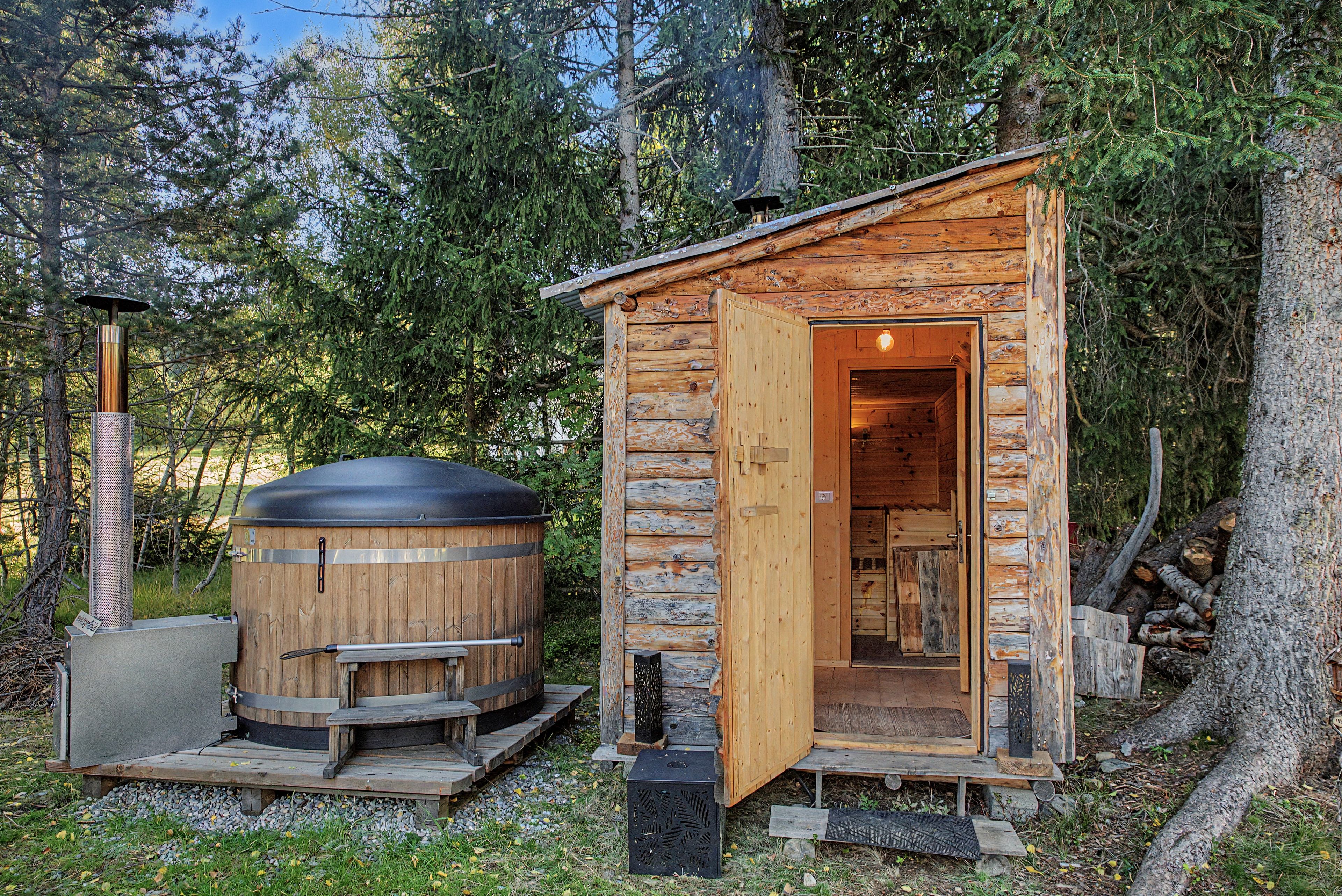 Un rustico cottage di legno con porta aperta, un grande scaldacqua cilindrico e un comignolo in metallo.