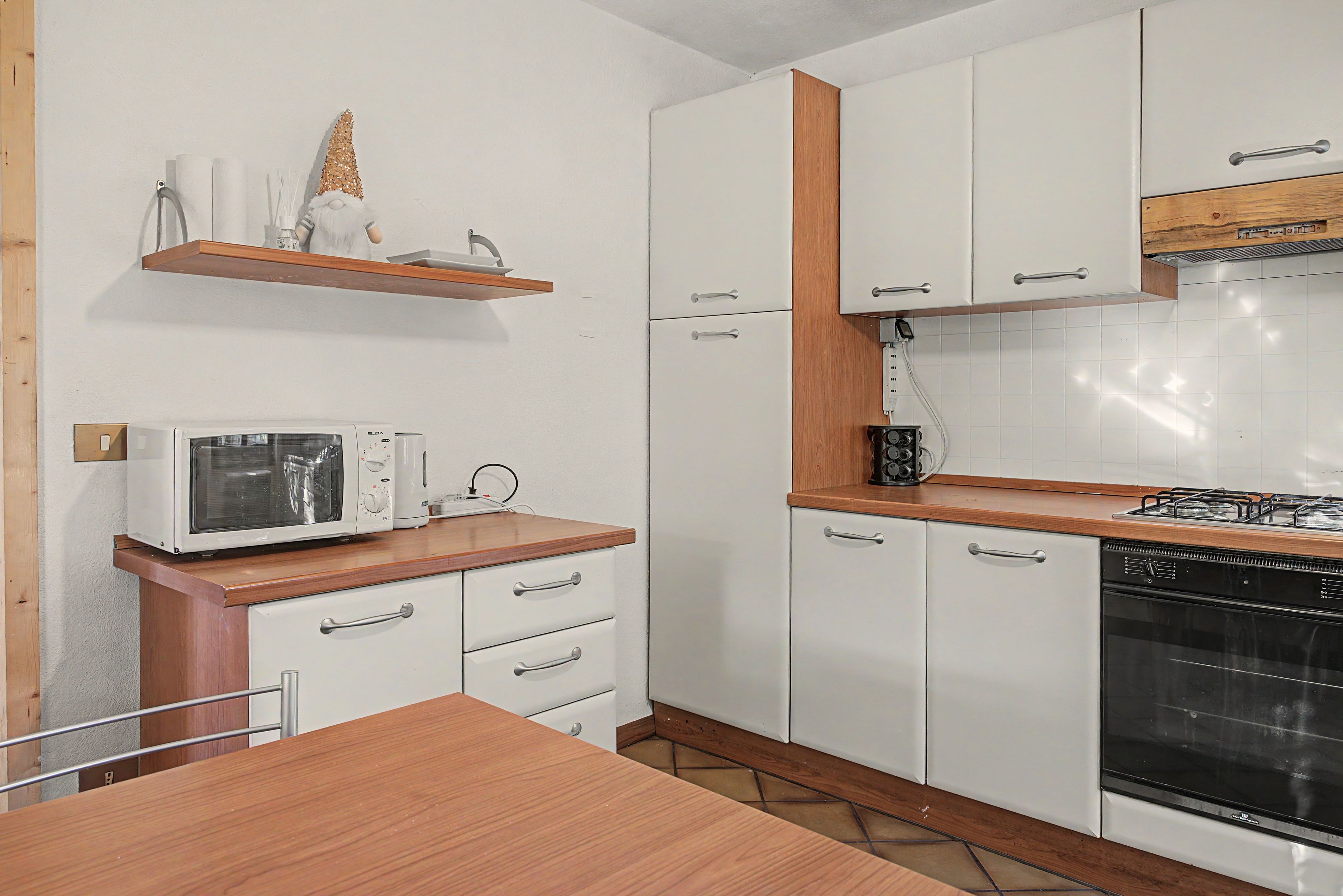 A kitchen with white cabinets, a microwave, a stove, and a wooden countertop.
