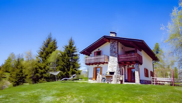 Ein zweistöckiges Haus mit einer Steinaußenwand, einem Balkon und einer Holzterrasse.