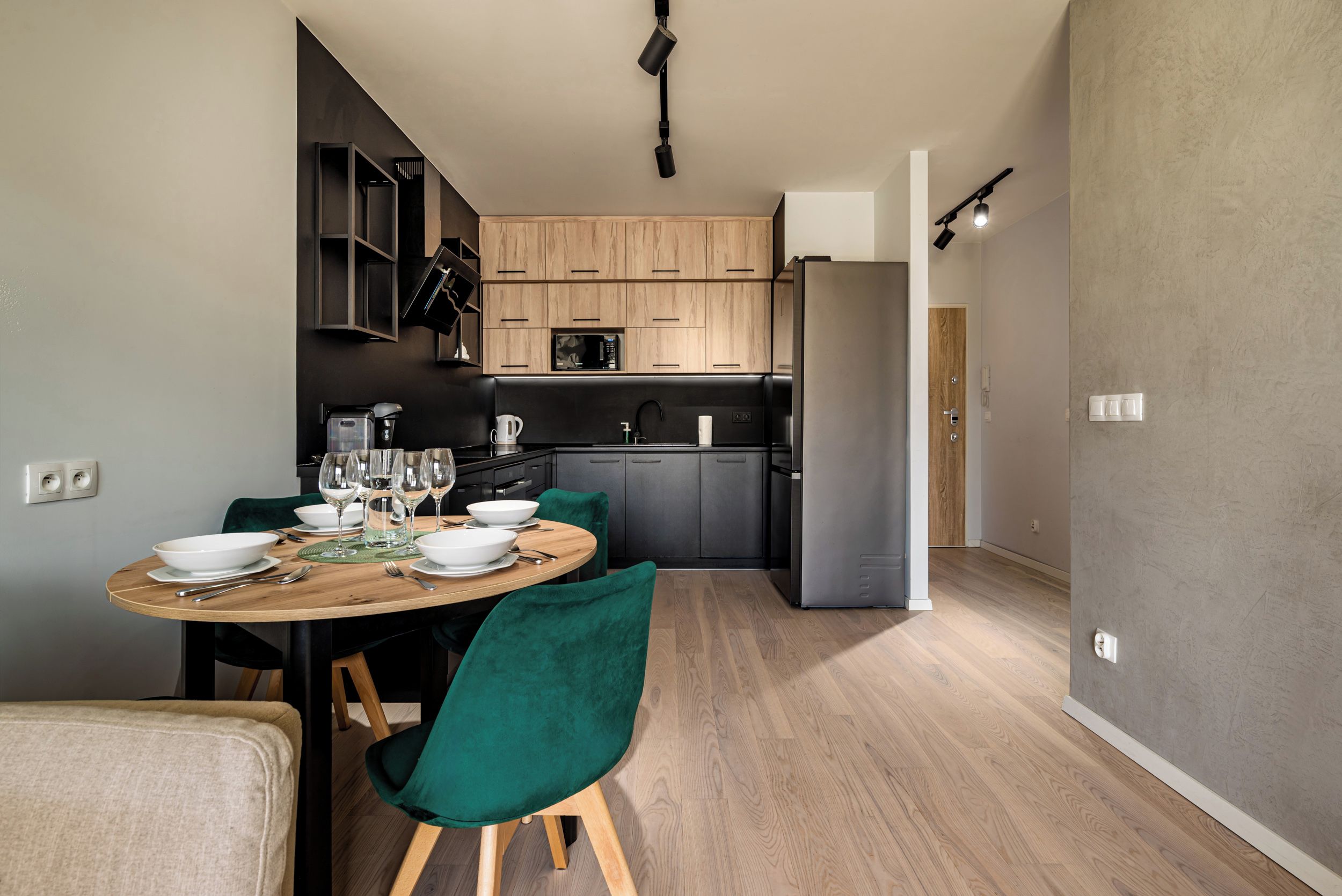 Una cocina moderna con armarios de madera, un microondas integrado y un refrigerador de acero inoxidable.