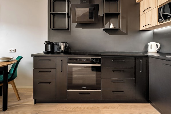 A modern kitchen with a built-in dishwasher, oven, and a coffee maker on the counter. - RentPlanet - Apartament Wichrowa (Wrocław)