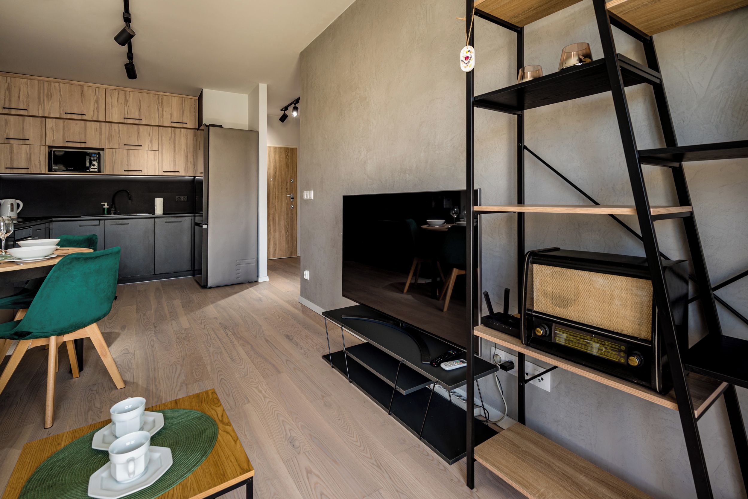 Eine moderne Küche mit Holzschränken, einer eingebauten Mikrowelle und einem Essbereich mit einem grünen Stuhl und einem Tisch, gedeckt mit weißen Geschirr.