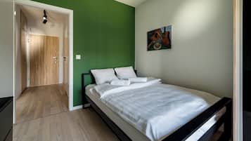 Un dormitorio con una cama, una pared verde y una puerta que da a otra habitación.