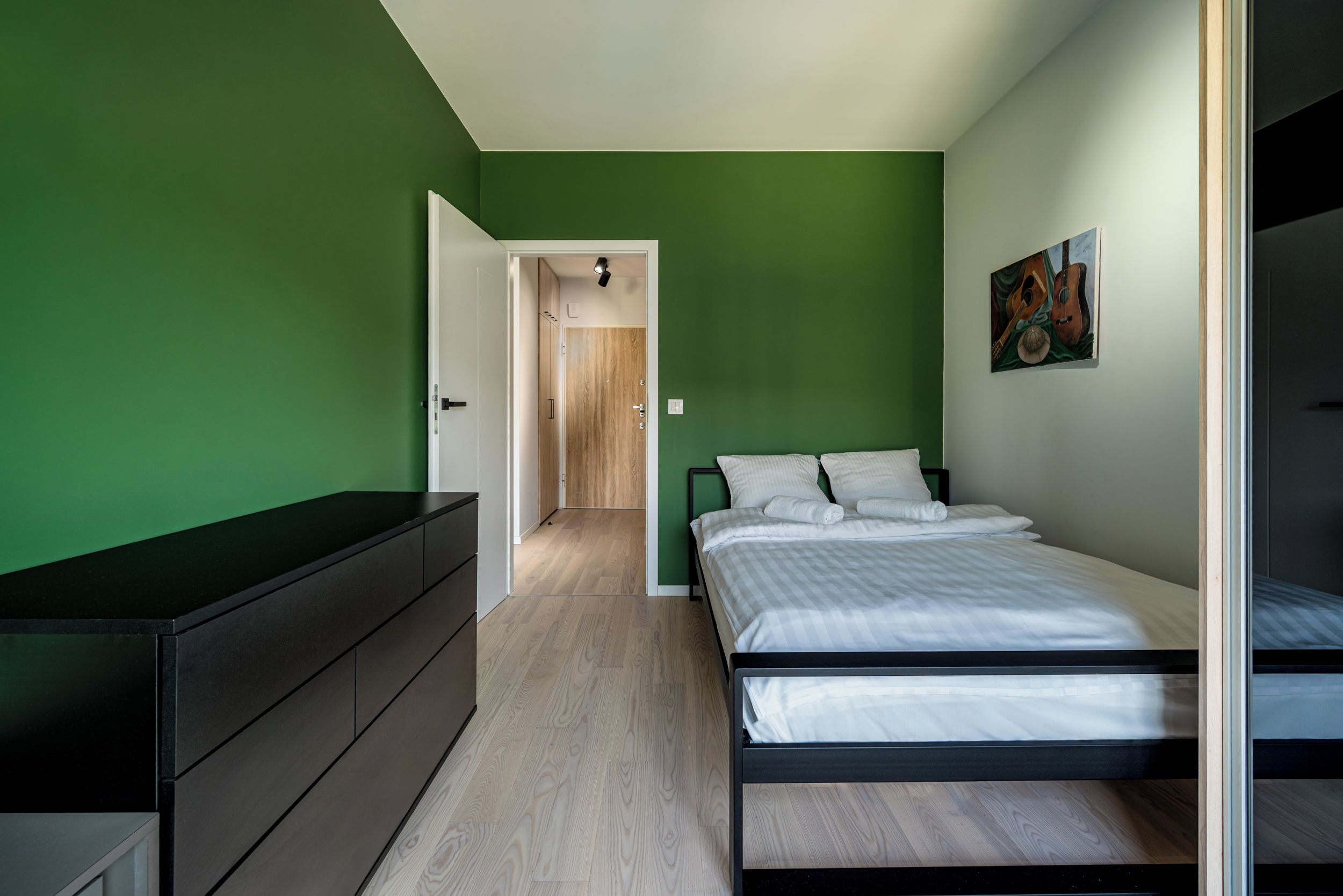 Een slaapkamer met een bed, een kaptafel en een schilderij aan de muur.