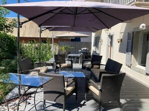 An outdoor patio with wicker furniture and a large umbrella providing shade. - Holiday Home in Trevigin With Wi-fi (Trevignin)