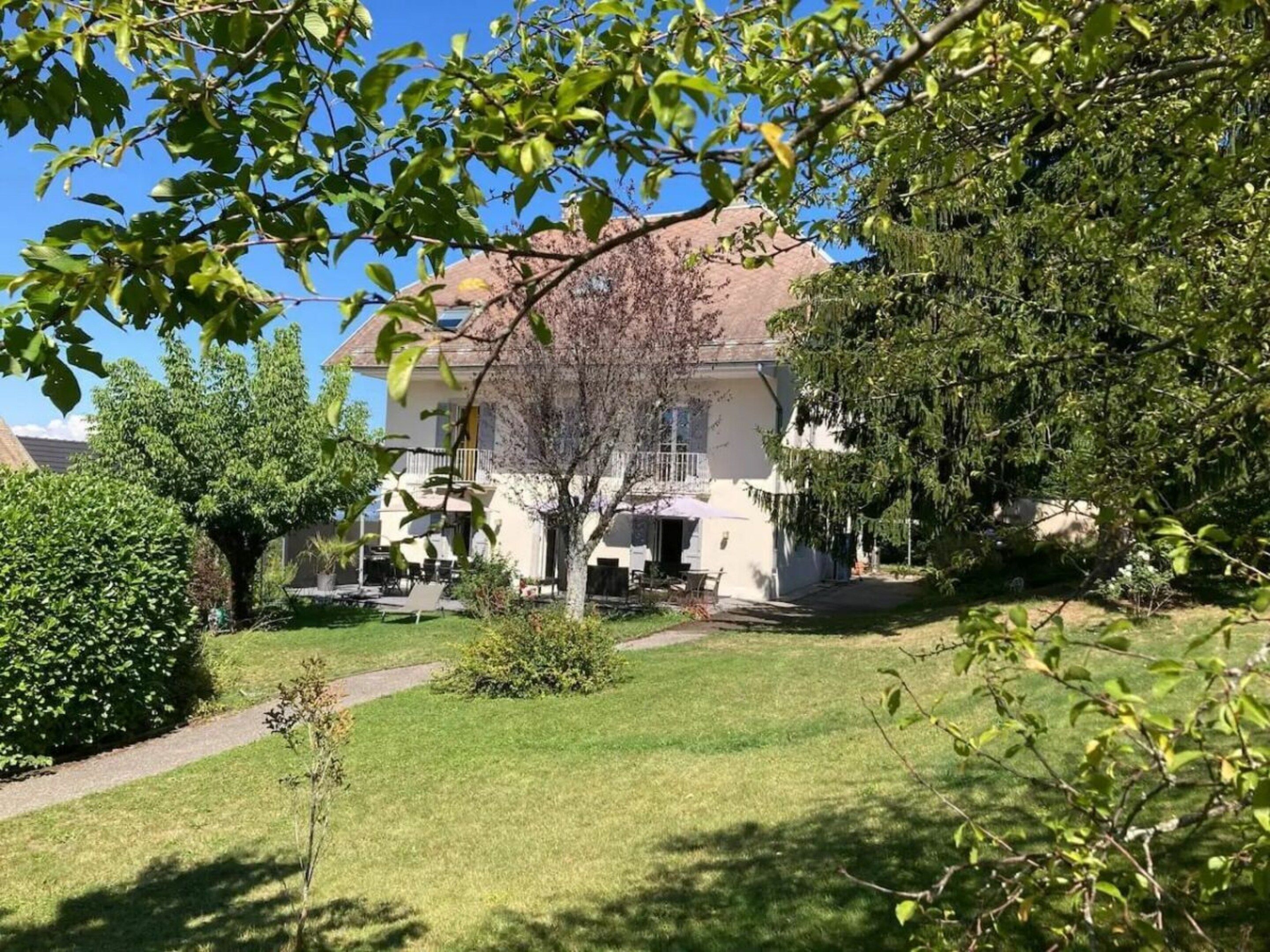 A residential property with a well-maintained lawn, a pathway leading to the entrance, and a two-story house with a balcony.