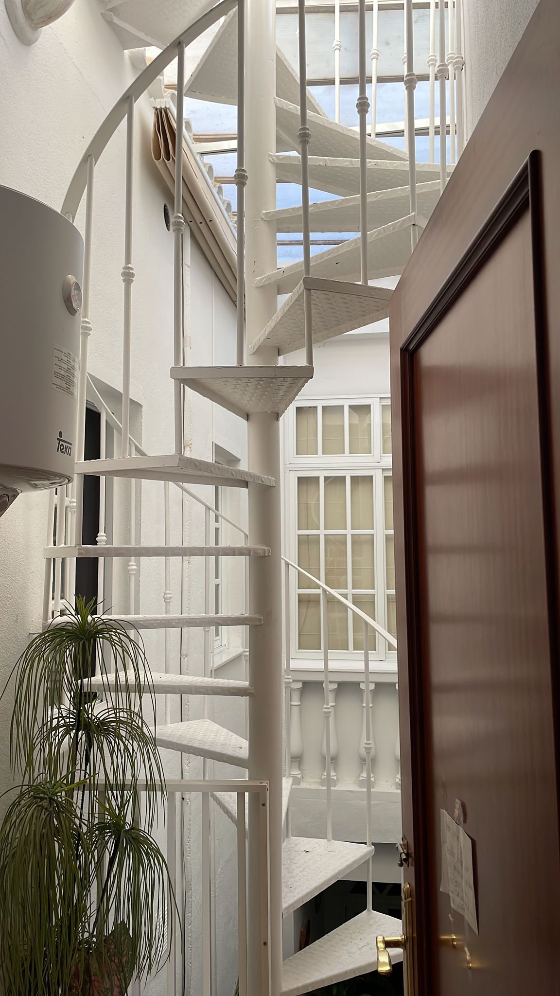 A spiral staircase with white railings and a wooden door with a brass handle.
