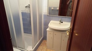 Une salle de bain avec une douche, un lavabo et un miroir.