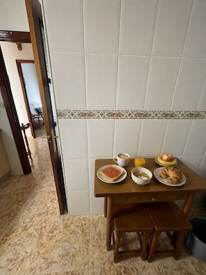Ein Essbereich mit einem Tisch, gedeckt für das Frühstück, inklusive Toast, Getreideflocken, einem Croissant, einer Tasse Kaffee und einem Glas Orangensaft.