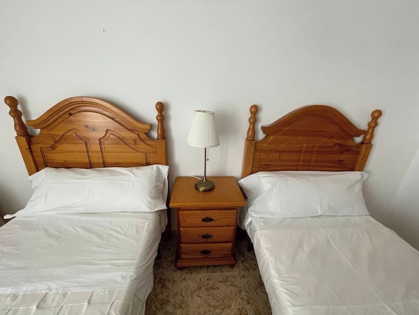 Ein Doppelbett mit Holzüberbau, ein Nachttisch mit Lampe und eine kleine Holzkommode.