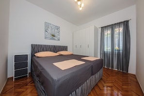 Un dormitorio con una cama grande, una mesita de noche, un armario y una ventana con cortinas.