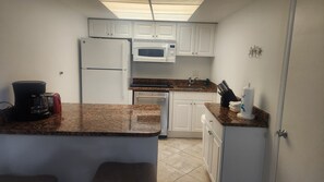 A compact kitchen with white cabinets, a microwave, a refrigerator, a coffee maker, and a sink. - 2 Bdrm unit ON VANDERBILT BEACH. Oct 24-31 (Naples)