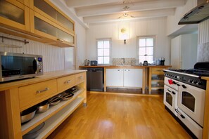A modern kitchen with wooden cabinets, stainless steel appliances, and a central island. - Villa Richemont - Panoramic Views & Private Pool (Brantôme en Périgord)