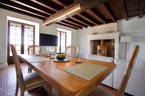 A dining area with a wooden table, chairs, and a fireplace. - Villa Richemont - Panoramic Views & Private Pool (Brantôme en Périgord)