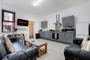 Un appartement moderne comprenant un salon, une kitchenette et un téléviseur diffusant du contenu « NETFLIX ».