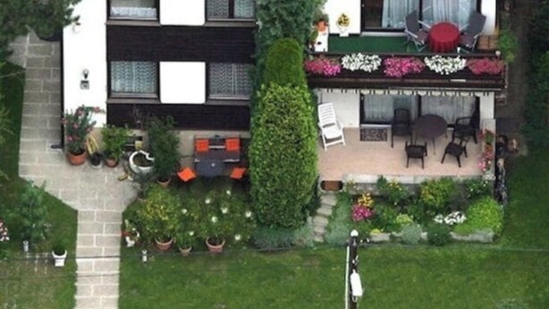 Ein zweistöckiges Gebäude mit Balkon, Außenbereich zum Sitzen und einem geparkten Auto davor.