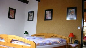 Ein Einzelbett mit Holzrahmen, ein Nachttisch mit Lampe sowie eine Wand mit gerahmten Bildern.