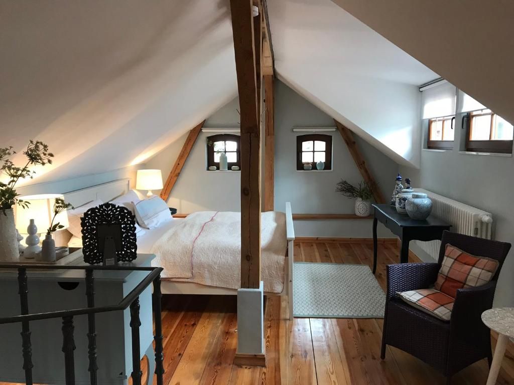 A cozy attic bedroom with a bed, a chair, a table, and a radiator.