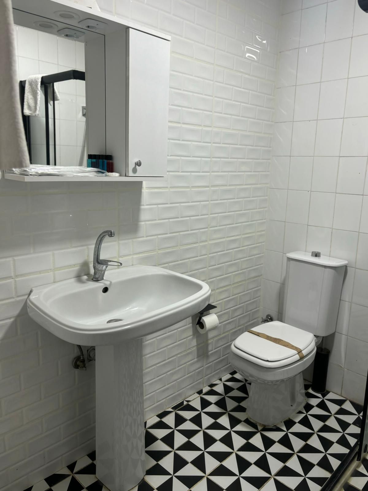 A bathroom with a white sink, toilet, and tiled floor.
