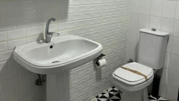 A bathroom with a white sink, toilet, and tiled floor.