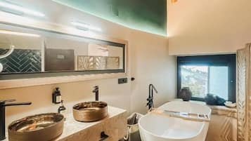 A modern bathroom with a freestanding bathtub, a large mirror, and a countertop with two sinks.