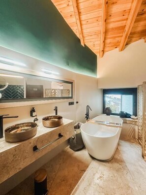 A modern bathroom with a freestanding bathtub, a large mirror, and a countertop with two sinks. - Hotel Poeta Jorge Manrique (Segura de la Sierra)