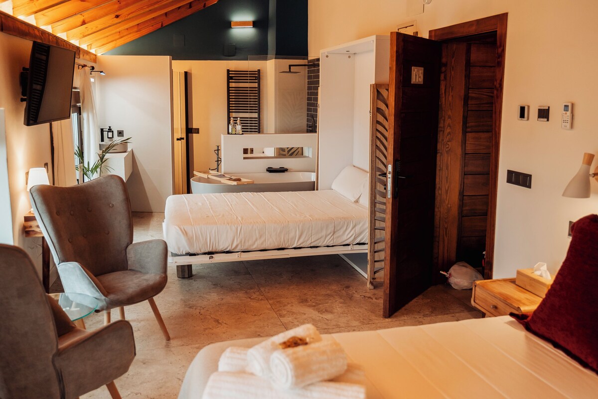 A modern bedroom with a bed, a chair, a bedside table, and a wooden door.