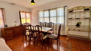A dining area with a wooden table and chairs, a cabinet, and a metal shelf unit.
