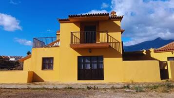 A yellow two-story building with a balcony, a window, and a door.