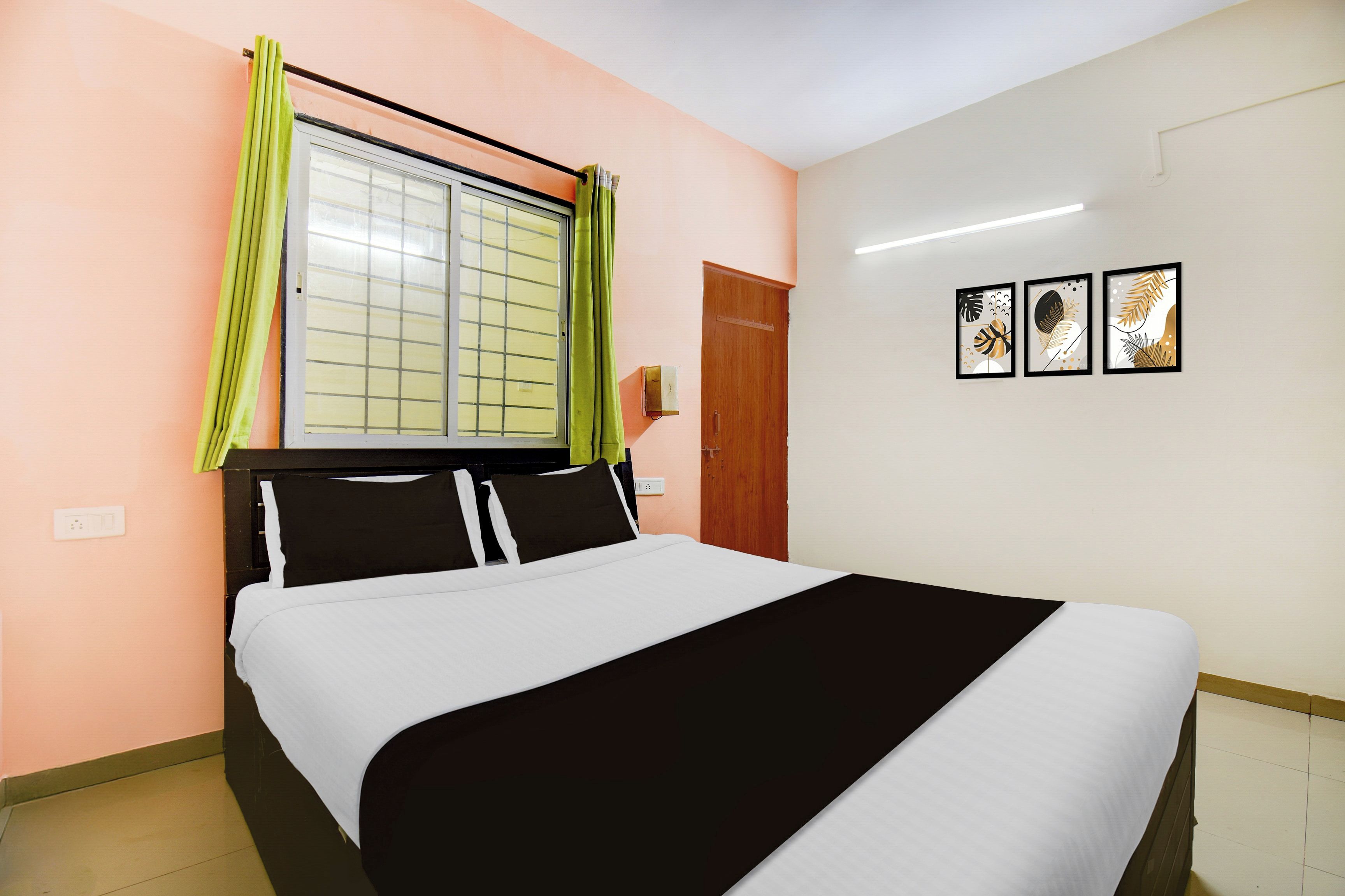 Une chambre à coucher avec un lit, une fenêtre avec des rideaux, une porte et des œuvres d’art accrochées au mur.