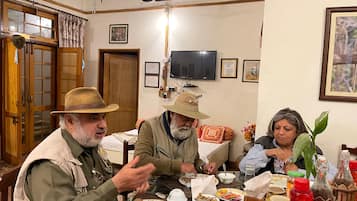 Un comedor con una mesa dispuesta para cuatro personas, un televisor montado en la pared y una puerta de madera con paneles de vidrio.
