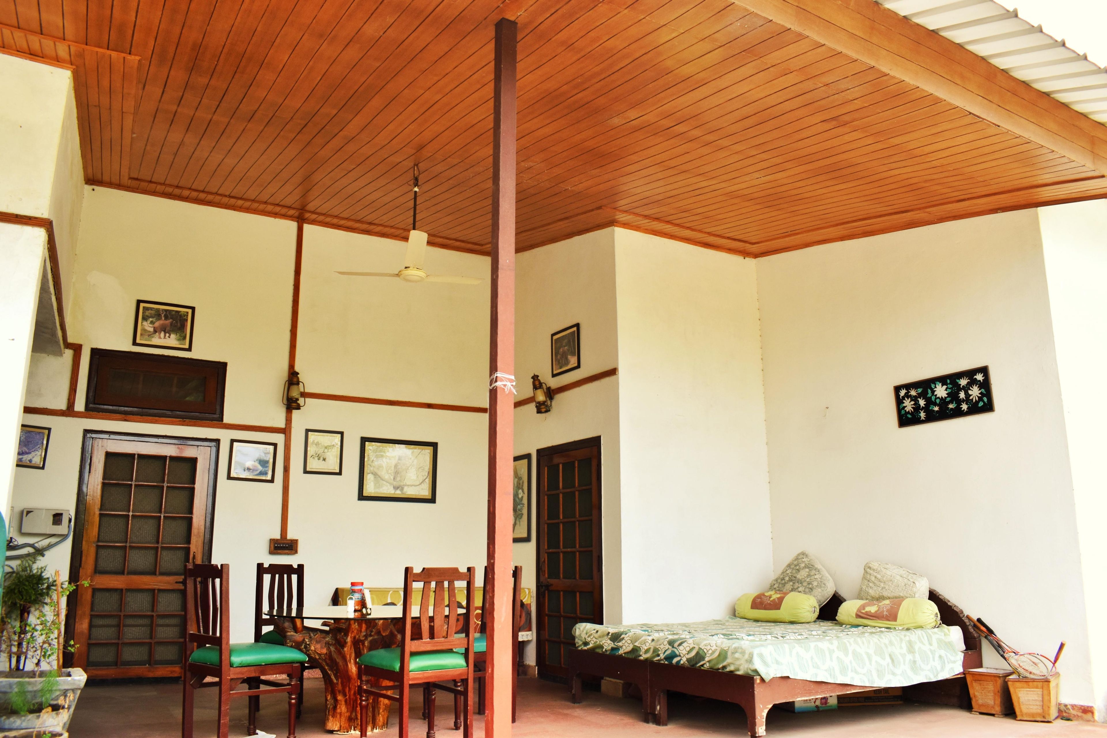 Una habitación con techo de madera, una mesa de comedor con sillas, una cama con almohadas y una pared con cuadros enmarcados.