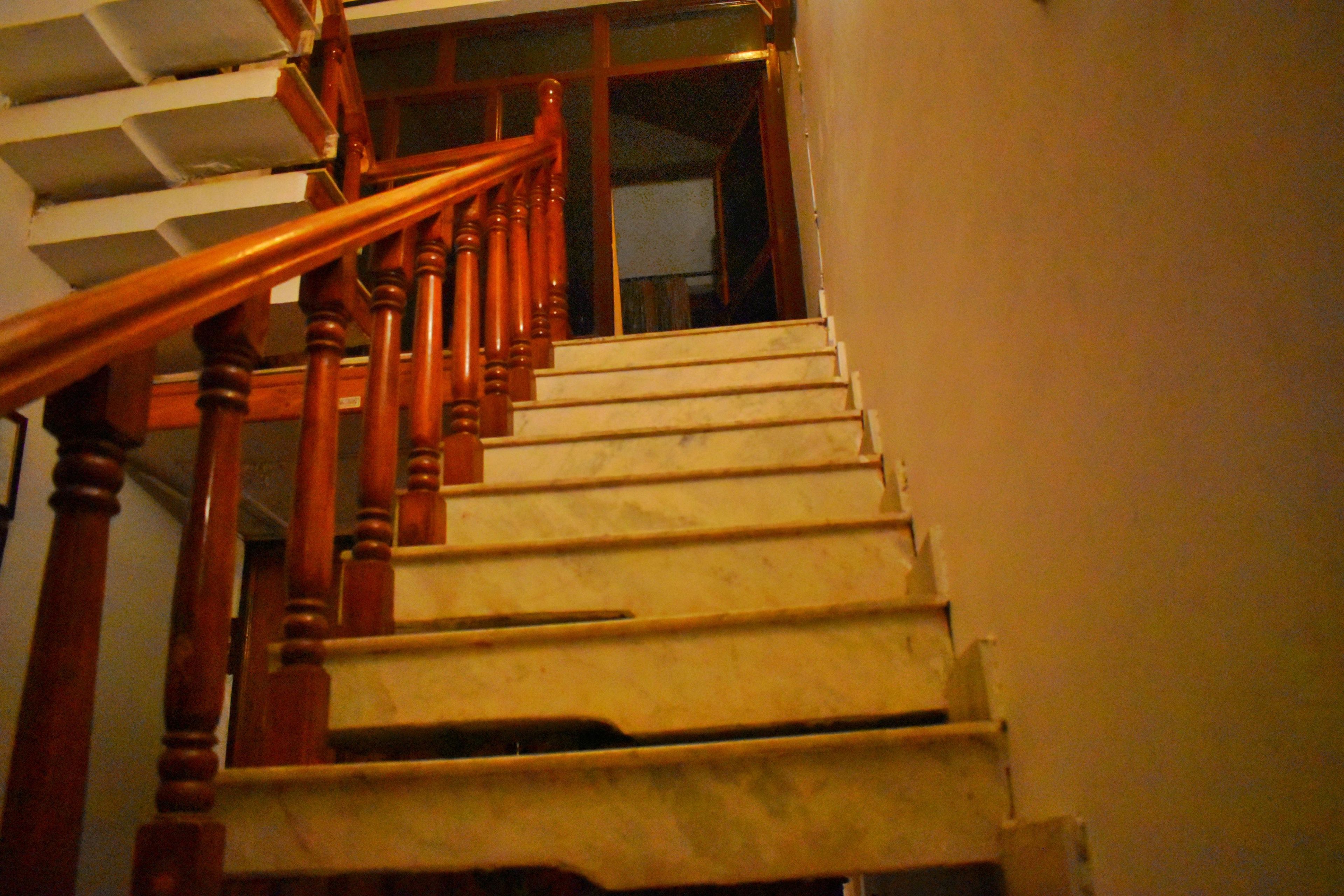 A wooden staircase with a handrail leading to a landing.