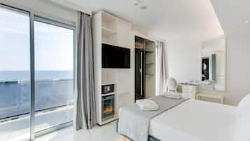 Una habitación de hotel moderna con una cama grande, un televisor de pantalla plana, un vestidor y un balcón con vistas a la ciudad.
