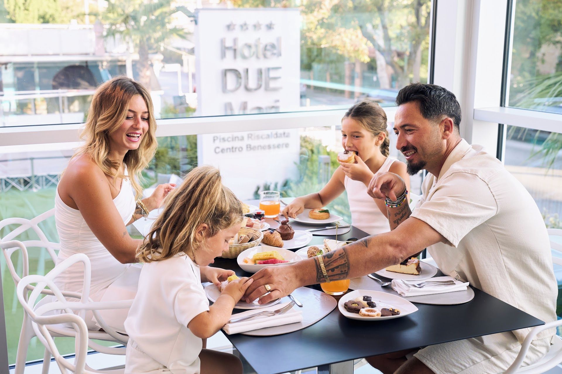 A family dining at a table with a view of a hotel sign and a sign for a pool.