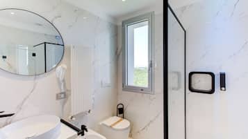 Ein modernes Badezimmer mit einem runden Spiegel, einem weißen Waschbecken, einer Toilette und einer Duschkabine.
