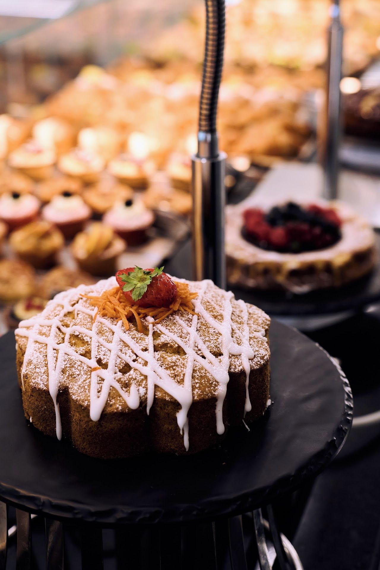 Una presentación de postres con varios pasteles y productos de repostería, incluyendo un pastel con cobertura blanca y una decoración de fresa.