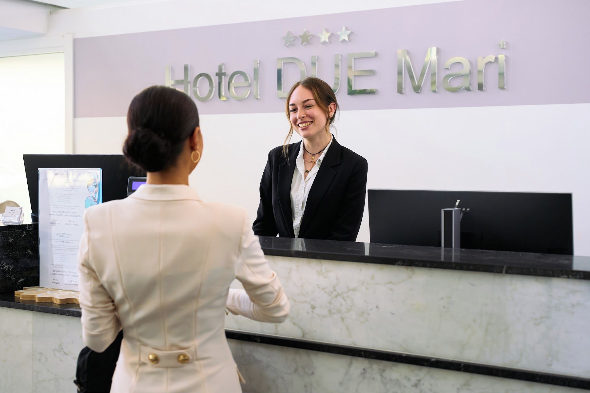 Una recepción de hotel con un letrero que dice 'Hotel BLUE Mari' y un monitor de computadora.