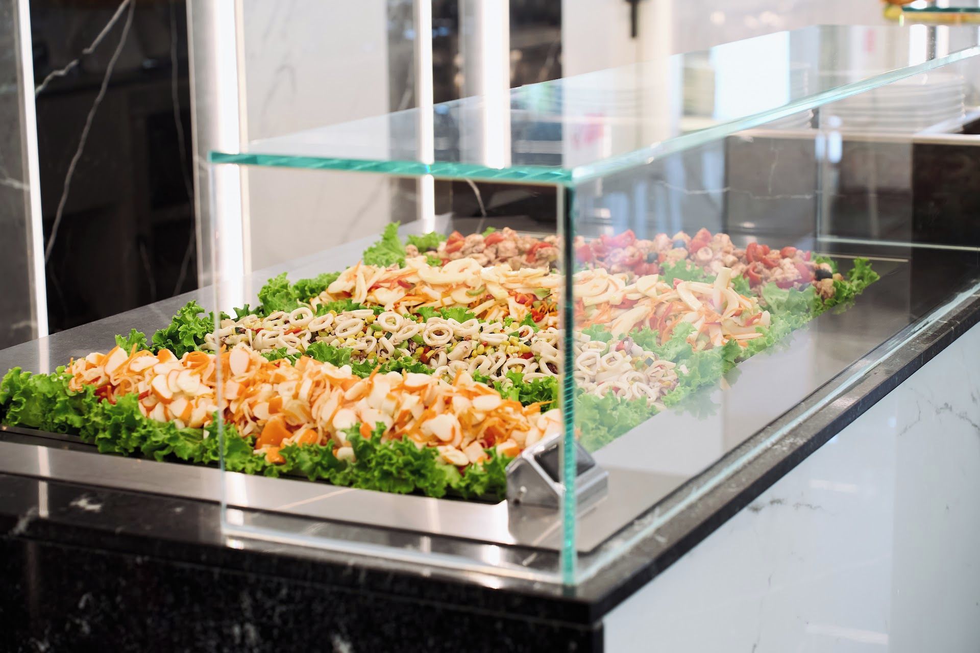Un buffet où diverses préparations culinaires sont présentées dans une vitrine.