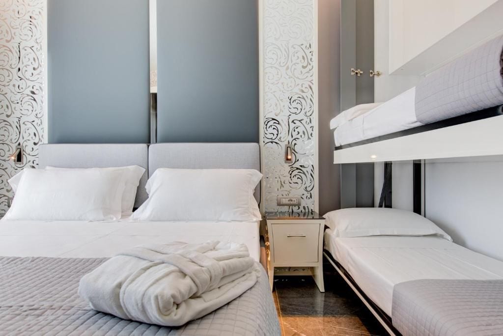 Una habitación de hotel con literas, una mesita de noche y otra mesita auxiliar.
