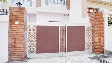 Una entrada protegida con una reja metálica decorativa y un muro de ladrillo.