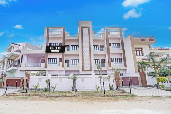 A multi-story hotel with a central vertical decorative element, balconies, and a clear sky. - Hotel O Garden View Vrindavan Lucknow (Lucknow)