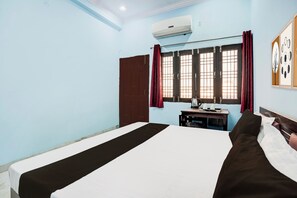 A bedroom with a bed, a window with curtains, a radiator, and a wall-mounted air conditioner. - Hotel O Garden View Vrindavan Lucknow (Lucknow)